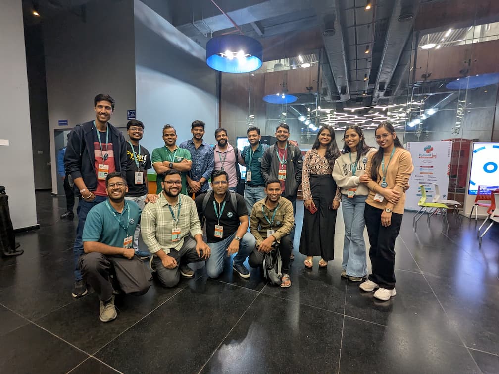 Group photo of approximately 15 smiling attendees and organizers at PyConf Hyderabad 2025, posing together with conference badges and lanyards in front of the PyConfHyd 2025 banner.